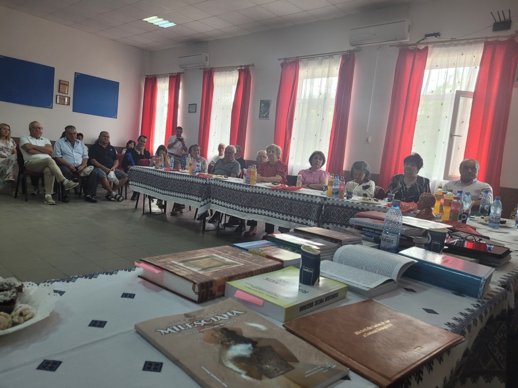 Participanți la întâlnirea culturală din Dodești, cu volume de carte expuse în prim-plan.
