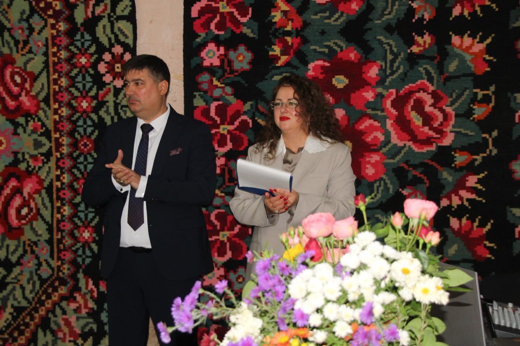 Svetlana și Victor Gheciu, gazdele lansării volumului „Ephemer”, în fața covoarelor tradiționale și a aranjamentelor florale.